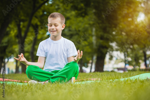 Photo: happy kid is doing exercises in the park happy kid is doing exercises in the park