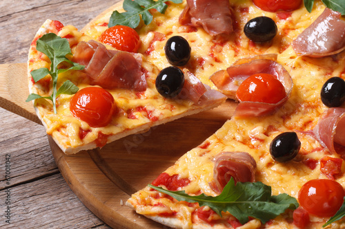 Photo: piece of pizza with ham, tomatoes, black olives and arugula piece of pizza with ham, tomatoes, black olives and arugula