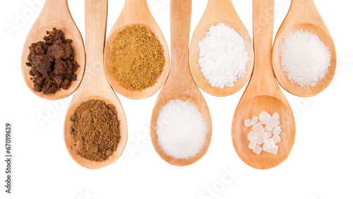 Photo: Various type of sugar on wooden spoon over white background Various type of sugar on wooden spoon over white background