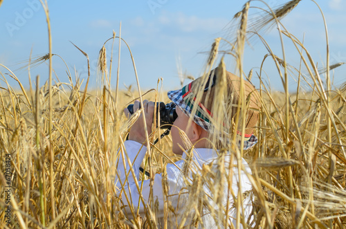 Photo: Little boy hiding in a wheat field bird watching Little boy hiding in a wheat field bird watching