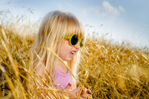 Photo: Cute little girl wearing sunglasses, in a warm day Cute little girl wearing sunglasses, in a warm day