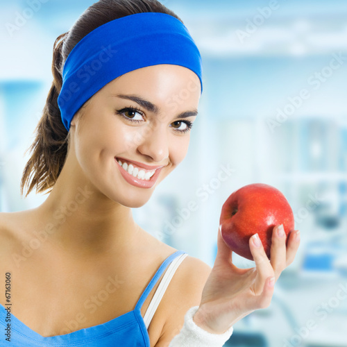 Photo: Woman in sportswear with apple, at gym Woman in sportswear with apple, at gym