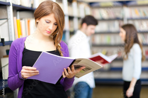 Photo: Woman holding a book in a library Woman holding a book in a library