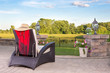 Vacant wicker armchair overlooking a tranquil pond Vacant wicker armchair overlooking a tranquil pond