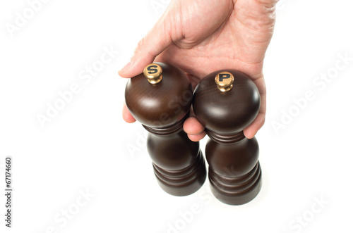 Photo: Asian male hand holding wooden salt and pepper shakers on white Asian male hand holding wooden salt and pepper shakers on white