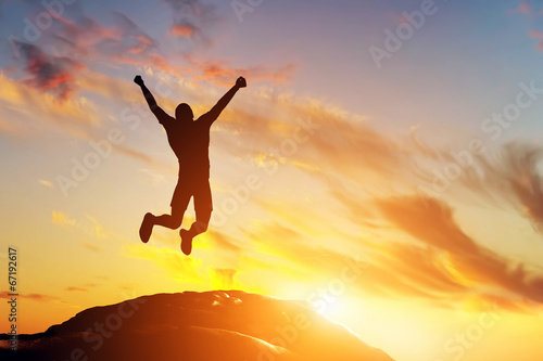 Happy man jumping for joy on the peak of the mountain. Success