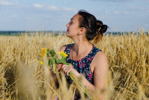 Photo: Laughing woman holding flowers in a wheat field Laughing woman holding flowers in a wheat field