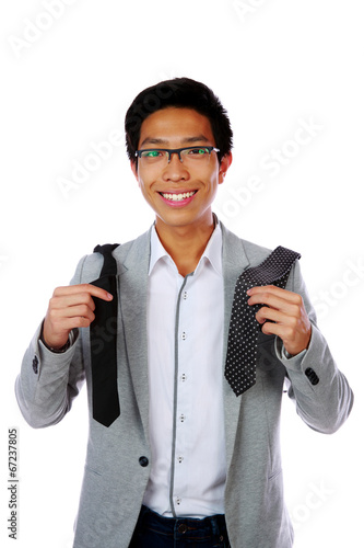 Photo: Happy asian man trying to choose a tie over white background Happy asian man trying to choose a tie over white background