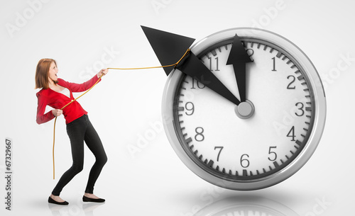 Photo: Woman pulling clock hands backwards Woman pulling clock hands backwards
