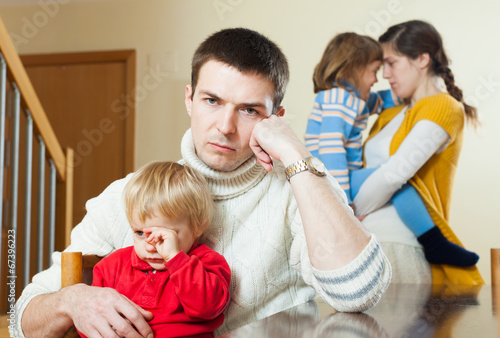 Photo: Young family conflict. Upset man against sadness woman Young family conflict. Upset man against sadness woman