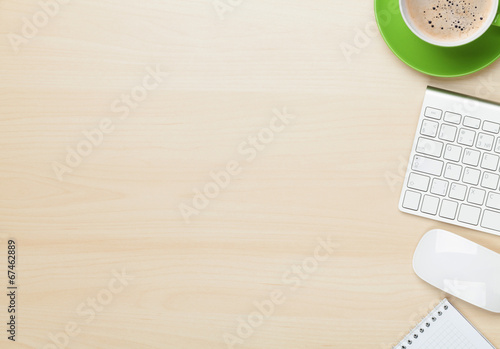 Photo: Office table with notepad, computer and coffee cup Office table with notepad, computer and coffee cup