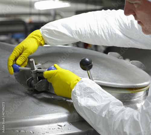 Photo: worker in yellow gloves closing industrial process tank worker in yellow gloves closing industrial process tank