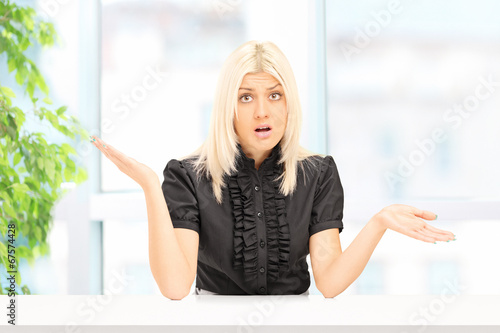 Photo: Woman gesturing uncertainty seated at home Woman gesturing uncertainty seated at home