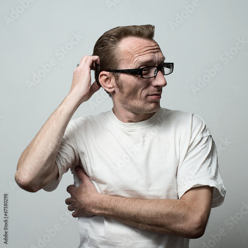 Photo: Unshaven Man in deep thought itching his head Unshaven Man in deep thought itching his head