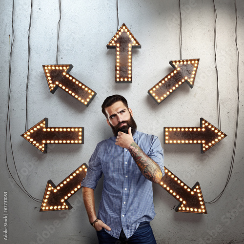 Photo: thoughtful bearded man and lighting arrows on a wall thoughtful bearded man and lighting arrows on a wall