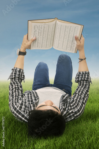 Photo: Student reads book outdoors Student reads book outdoors