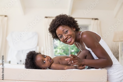 Photo: Happy mother with baby girl on changing table Happy mother with baby girl on changing table