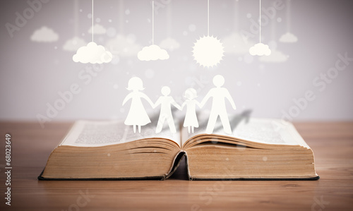 Photo: Cardboard figures of the family on opened book Cardboard figures of the family on opened book