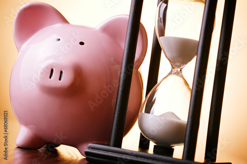 Photo: Pink piggy bank with a vintage hourglass behind Pink piggy bank with a vintage hourglass behind