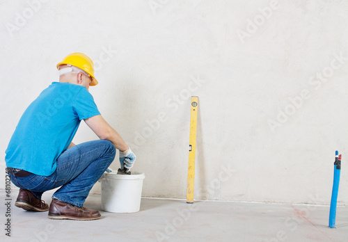 Photo: Plasterer man with trowel and bucket near plaster wall. Plasterer man with trowel and bucket near plaster wall.