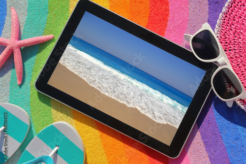 Photo: Tablet on beach towel with summer accessories Tablet on beach towel with summer accessories
