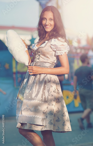 Photo: German Girl wearing a Dirndl and eating candyfloss German Girl wearing a Dirndl and eating candyfloss