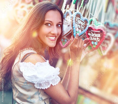 Photo: Woman in Dirndl costume with Gingerbread heart Woman in Dirndl costume with Gingerbread heart