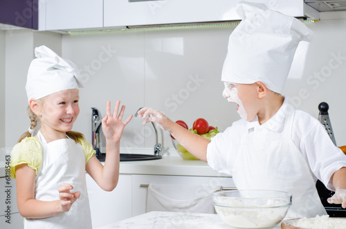 Photo: Happy little boy and girl baking in the kitchen Happy little boy and girl baking in the kitchen