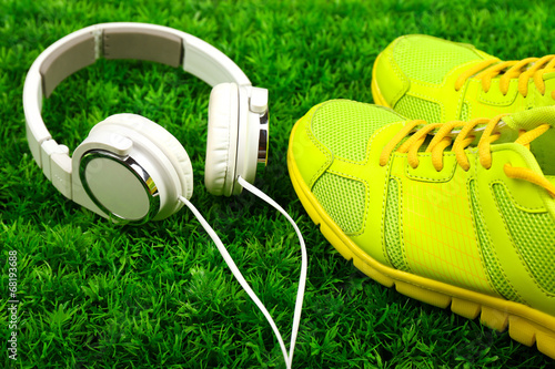 Photo: Sport shoes and headphones on green grass background Sport shoes and headphones on green grass background