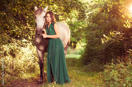 Photo: young woman with white horse at forest path young woman with white horse at forest path