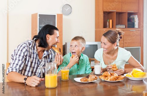 Photo: family having breakfast with croissants and juice family having breakfast with croissants and juice