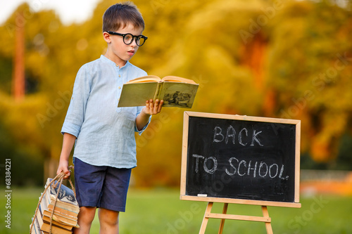 Photo: Cute little schoolboy reading book Cute little schoolboy reading book