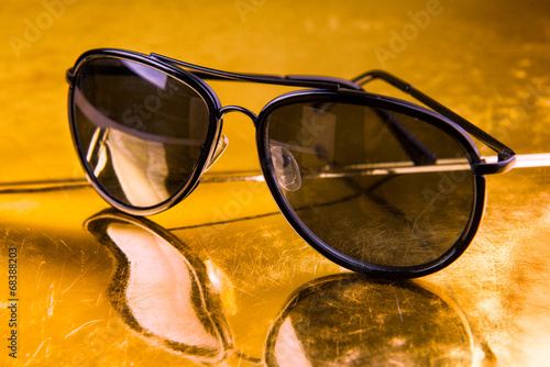 Photo: Luxury aviator sunglasses on golden background Luxury aviator sunglasses on golden background