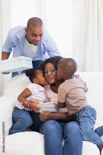 Photo: Happy family on the couch giving mother presents Happy family on the couch giving mother presents
