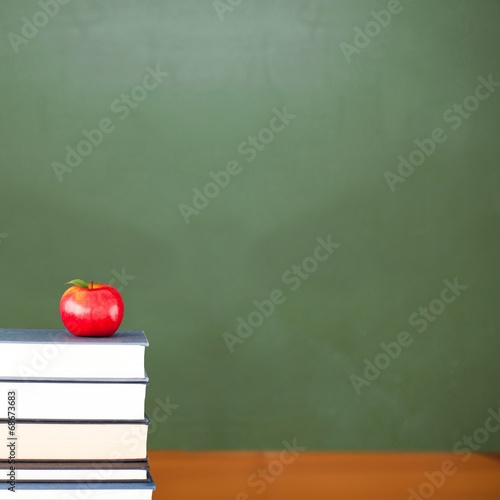 Photo: Red apple on pile of books in classroom Red apple on pile of books in classroom