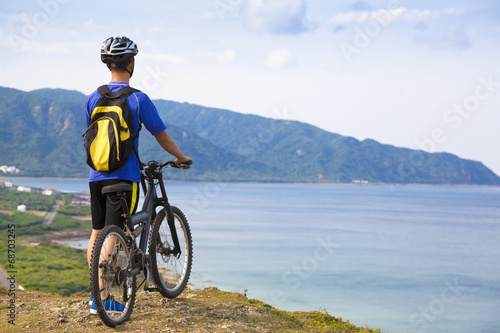 Photo: young man standing on the mountain with bike young man standing on the mountain with bike