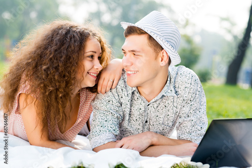 Photo: couple lying together in a park with laptop couple lying together in a park with laptop