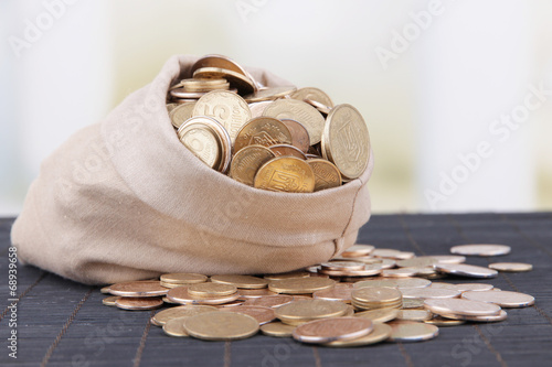 Photo: Fabric bag full of Ukrainian coins on wooden background Fabric bag full of Ukrainian coins on wooden background