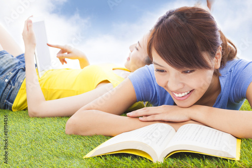 Photo: smiling pretty students lying on the grassland with books smiling pretty students lying on the grassland with books