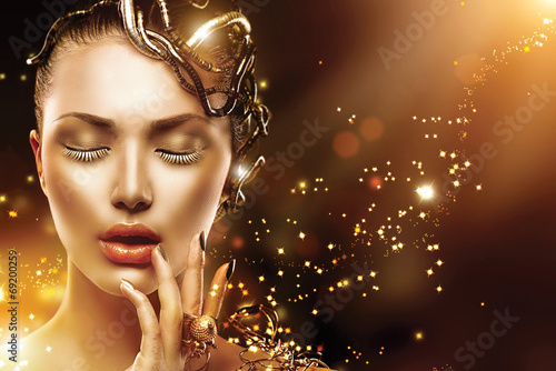 Photo: Model girl face with gold skin, nails, make-up and accessories Model girl face with gold skin, nails, make-up and accessories
