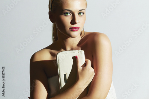 Photo: Beautiful blond woman.Fashion Stylish girl with white clutch Beautiful blond woman.Fashion Stylish girl with white clutch