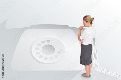 Photo: Thinking businesswoman against retro telephone Thinking businesswoman against retro telephone
