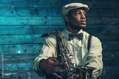 Fotoobraz na płótnie Afroamerykanin jazzowy muzyk z saksofonem przed starym wo