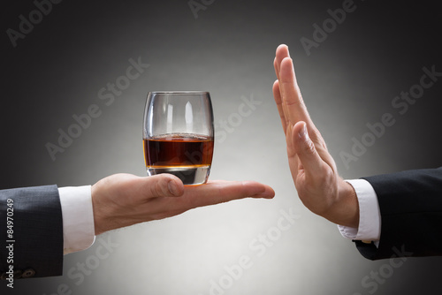 Businessman Rejecting Whisky Offered By Businessperson