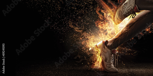 Fototapeta na wymiar Sport. Runner. Side view of a jogger legs with the power in the veins isolated on black. Fire and energy
