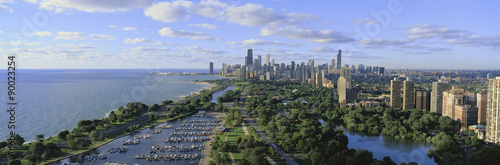 Plakat To pokazuje Lincoln Park, port Diversey z zacumowanymi łodziami, jezioro Michigan po lewej i panoramę w lecie. W mieście jest poranne światło.