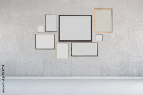 Viele Bilderrahmen an Wand aus Beton