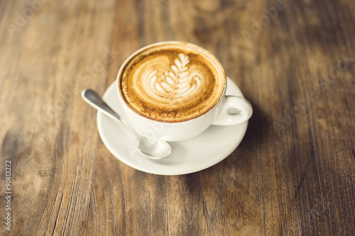Cup of cappuccino and teaspoon on a wooden table