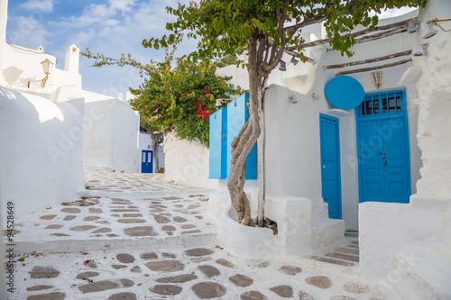  Mykonos traditional white streetview with blue door and trees, Greece