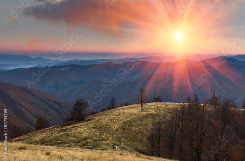 Colorful sunset in the autumn mountains.Tourist tents near forest.